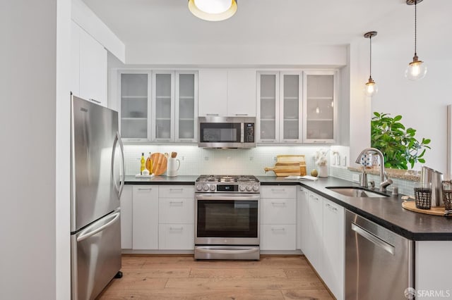 170 King St Unit 1006, San Francisco, CA 94107 - kitchen featuring stainless steel appliances, dark countertops, white cabinetry, backsplash, and light wood-style flooring