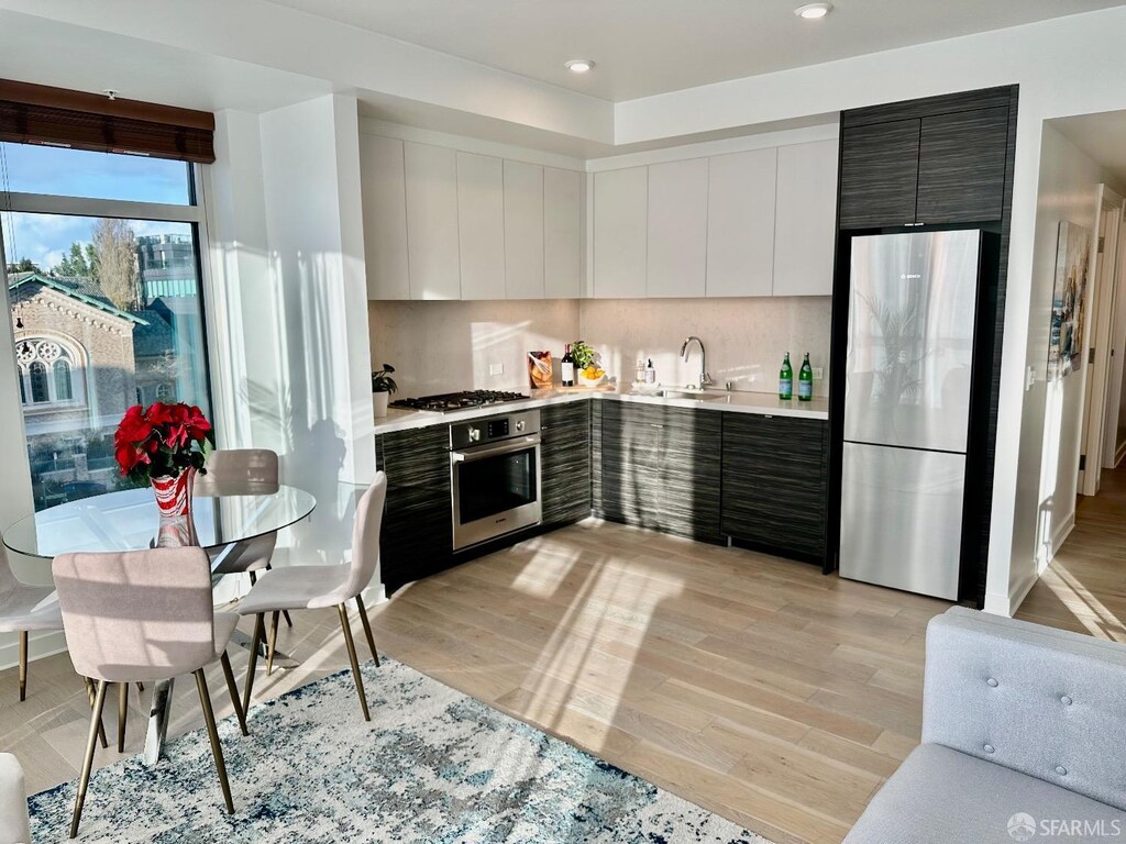 kitchen featuring light countertops, appliances with stainless steel finishes, light wood-style floors, a sink, and modern cabinets