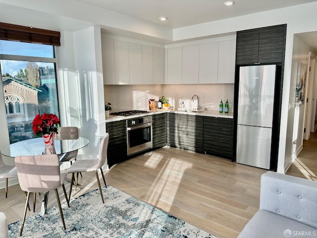 kitchen featuring light countertops, appliances with stainless steel finishes, light wood-style floors, a sink, and modern cabinets