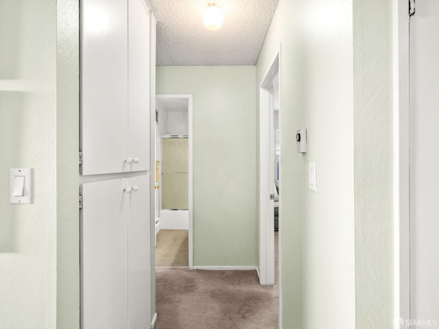 hallway featuring light carpet and a textured ceiling