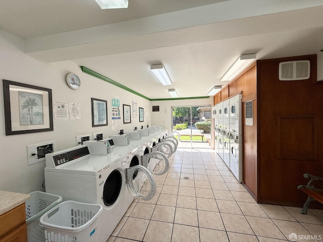 laundry area with light tile patterned floors, independent washer and dryer, and wooden walls