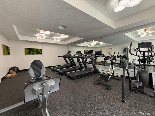 gym with a textured ceiling and a tray ceiling