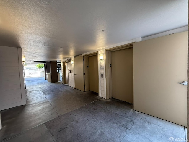 8100 Oceanview Ter Unit 117, San Francisco, CA 94132 - hallway featuring unfinished concrete flooring, elevator, and a textured ceiling