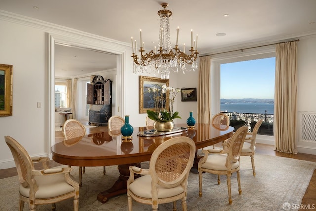 dining room featuring a water view, crown molding, an inviting chandelier, and wood-type flooring