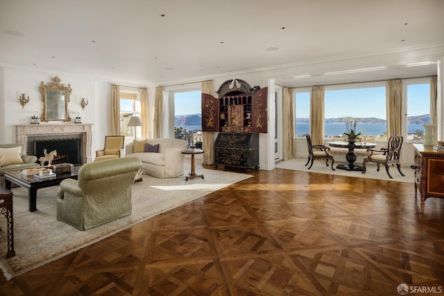 living room featuring a water and mountain view, ornamental molding, and parquet floors