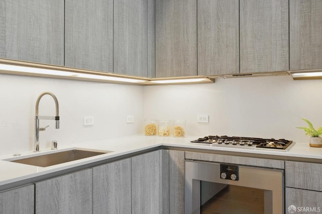 kitchen featuring wall oven, beverage cooler, sink, and stainless steel gas cooktop