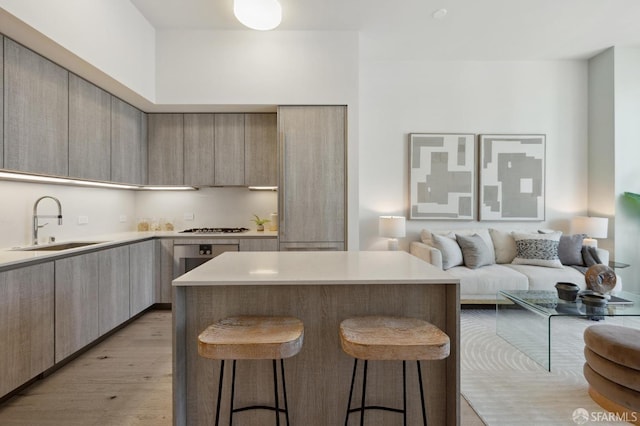 kitchen with light hardwood / wood-style floors, sink, a kitchen island, gas cooktop, and a kitchen breakfast bar