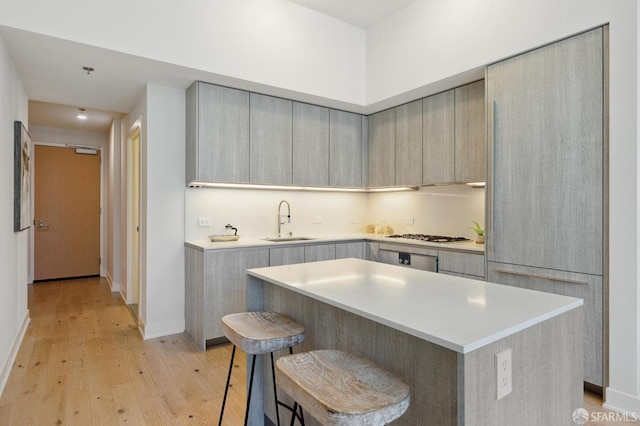 kitchen featuring a breakfast bar, a kitchen island, light hardwood / wood-style flooring, gas cooktop, and sink