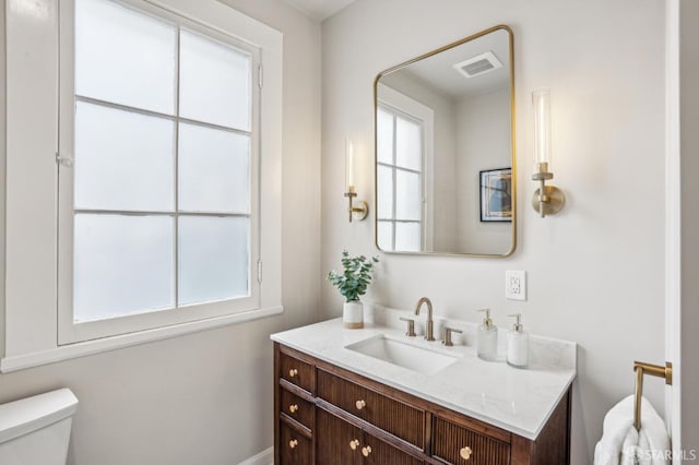 bathroom with visible vents, plenty of natural light, vanity, and toilet