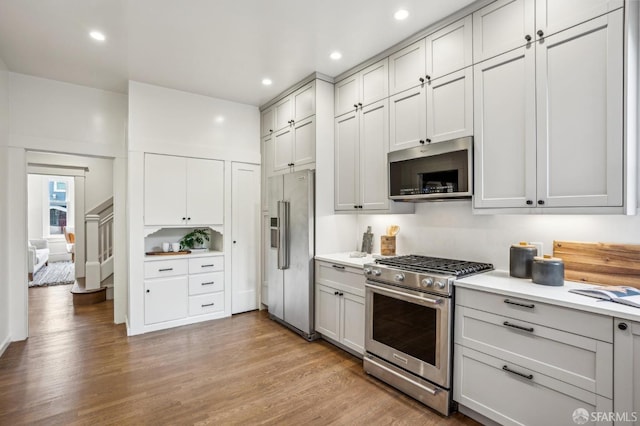 kitchen with recessed lighting, light countertops, light wood-style flooring, gray cabinetry, and appliances with stainless steel finishes