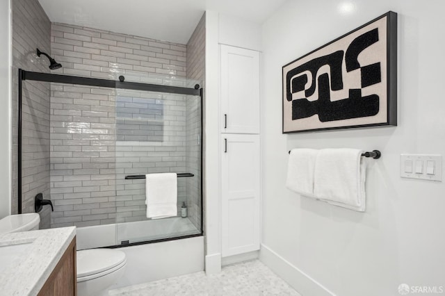 full bath featuring combined bath / shower with glass door, vanity, toilet, and baseboards