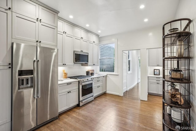 kitchen with stainless steel appliances, recessed lighting, light countertops, and light wood finished floors