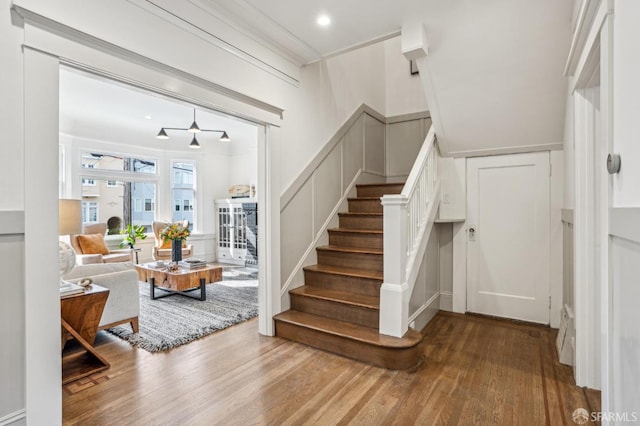 stairs featuring ornamental molding, a decorative wall, and wood finished floors