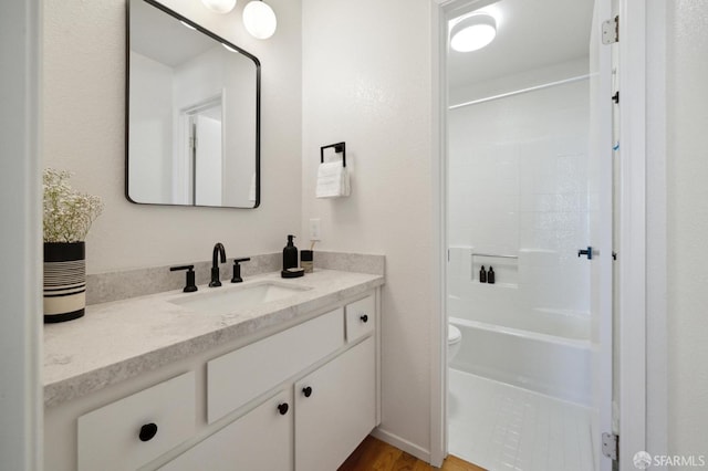 full bathroom with hardwood / wood-style floors, washtub / shower combination, vanity, and toilet