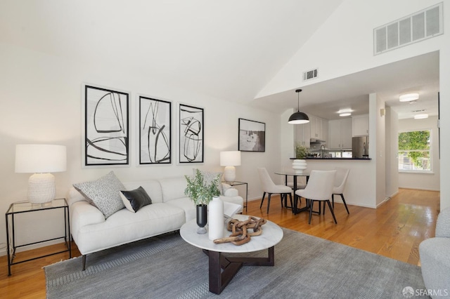 living room featuring light hardwood / wood-style floors and high vaulted ceiling