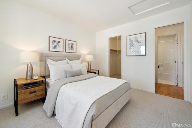 bedroom featuring a spacious closet, ensuite bathroom, a closet, and light carpet