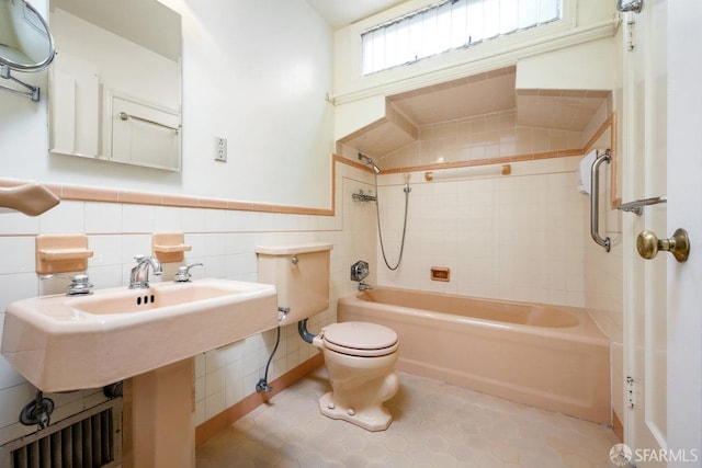 bathroom featuring tile patterned flooring, tile walls, toilet, and tiled shower / bath