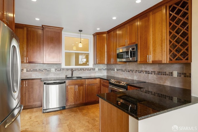 kitchen featuring sink, decorative light fixtures, dark stone countertops, appliances with stainless steel finishes, and kitchen peninsula