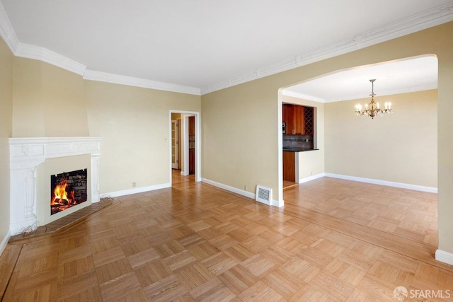 unfurnished living room with light parquet flooring, ornamental molding, and a notable chandelier