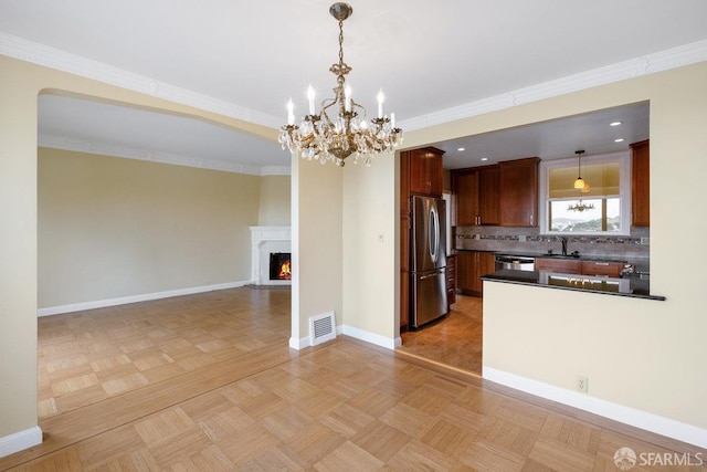 kitchen featuring pendant lighting, appliances with stainless steel finishes, decorative backsplash, and light parquet floors