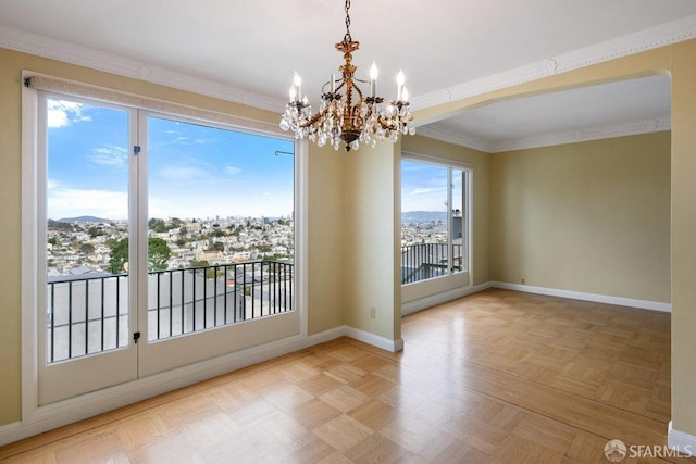 spare room featuring an inviting chandelier, ornamental molding, light parquet flooring, and a mountain view