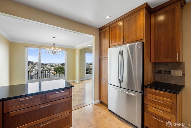 kitchen featuring tasteful backsplash, crown molding, stainless steel fridge, a notable chandelier, and pendant lighting