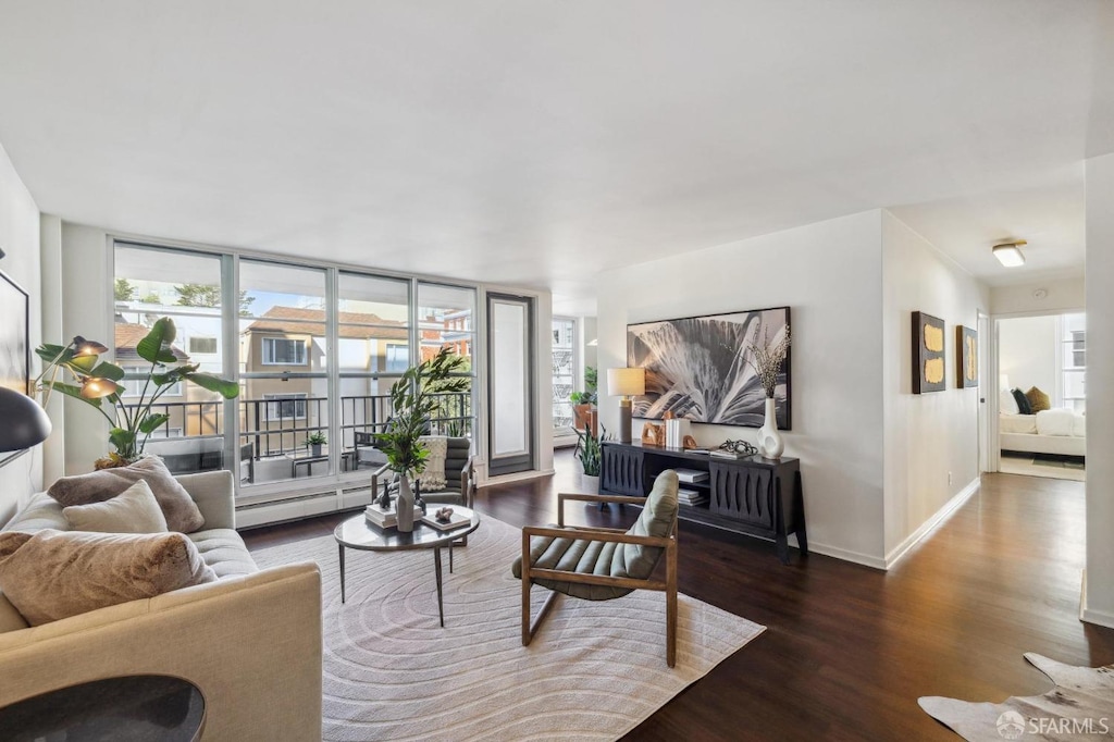 living room with dark hardwood / wood-style floors, expansive windows, and a baseboard heating unit