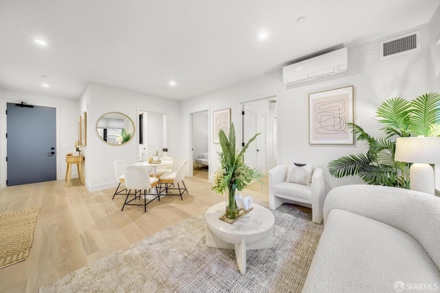 living room with a wall mounted air conditioner and light hardwood / wood-style flooring