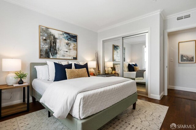 bedroom with crown molding, wood finished floors, baseboards, and a closet