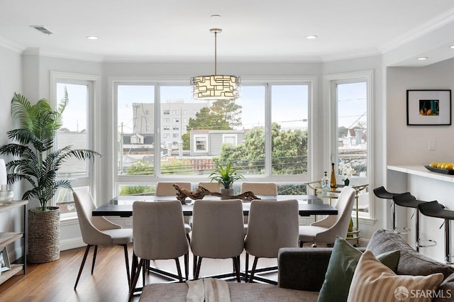 dining space featuring wood finished floors, crown molding, and a chandelier