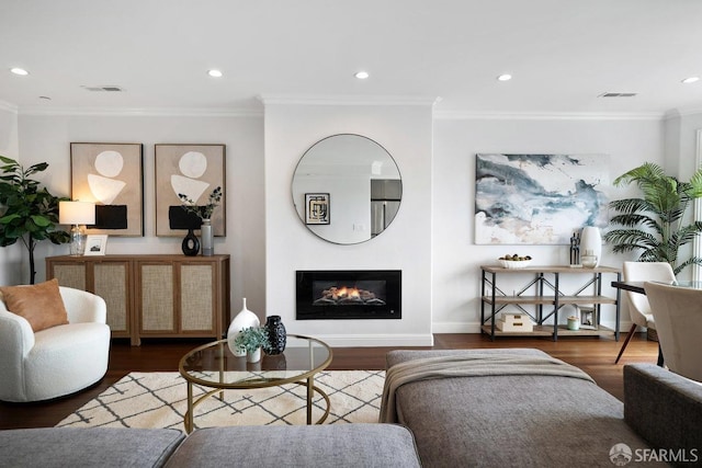living room with wood finished floors, crown molding, a glass covered fireplace, baseboards, and recessed lighting