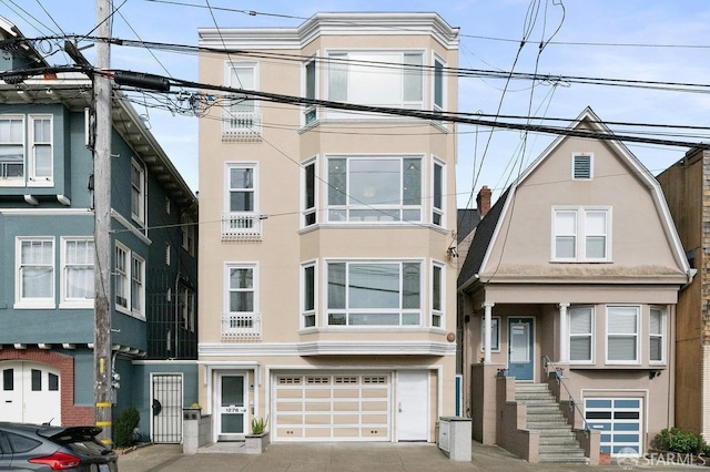 multi unit property featuring a garage, driveway, and stucco siding