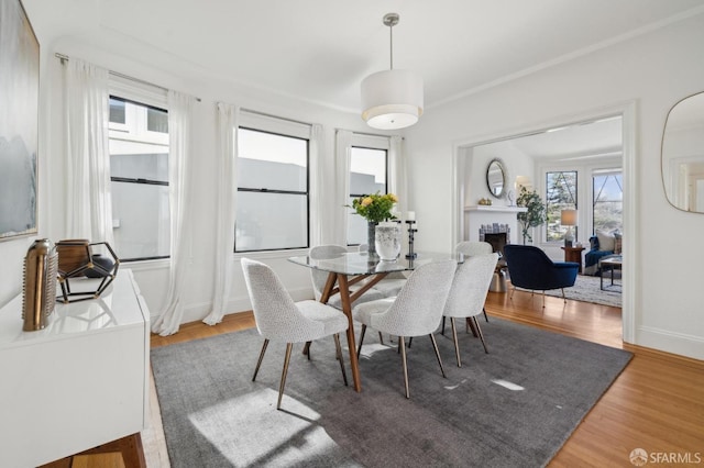 dining area with a fireplace, wood finished floors, and baseboards