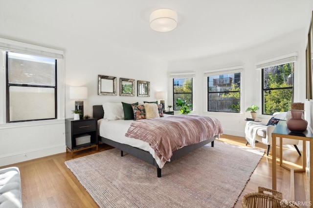 bedroom with baseboards, multiple windows, and light wood-style floors