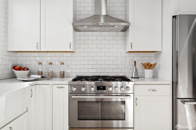 kitchen featuring wall chimney exhaust hood, appliances with stainless steel finishes, decorative backsplash, and light countertops