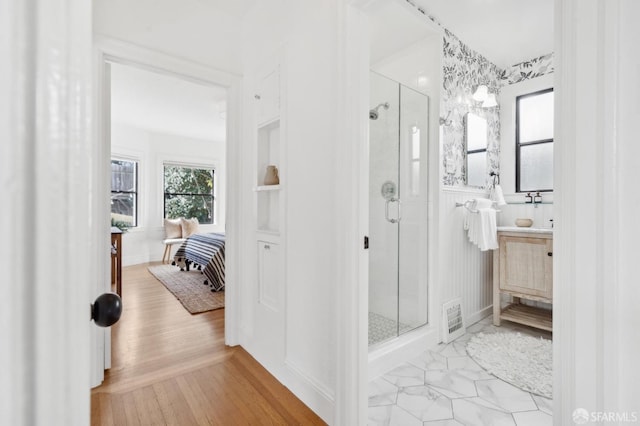 ensuite bathroom featuring wood finished floors, a stall shower, connected bathroom, and vanity