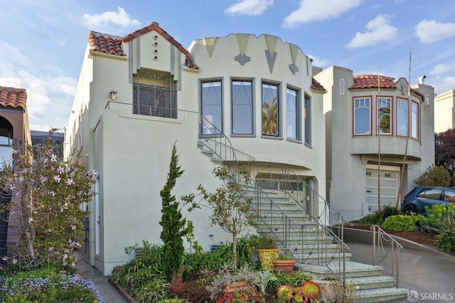 view of front of property with a tile roof, stairs, and stucco siding