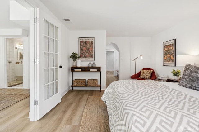 bedroom with arched walkways and light wood finished floors