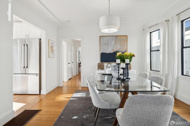 dining space featuring baseboards and light wood finished floors