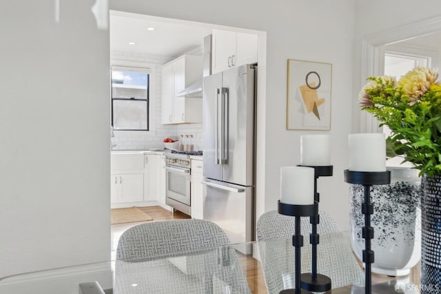 kitchen featuring stainless steel appliances, light wood-type flooring, white cabinets, and decorative backsplash