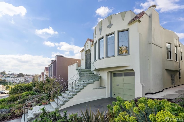 view of home's exterior featuring an attached garage, stairs, and stucco siding