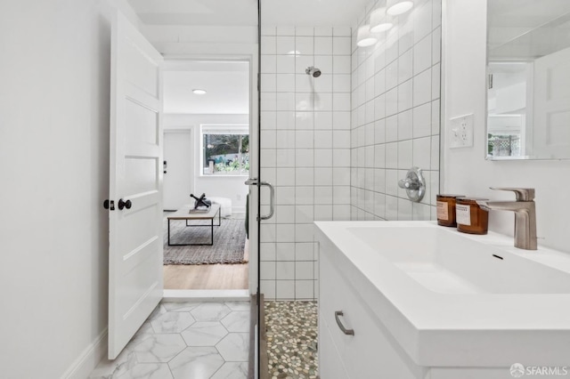 full bath with a tile shower, tile walls, and vanity