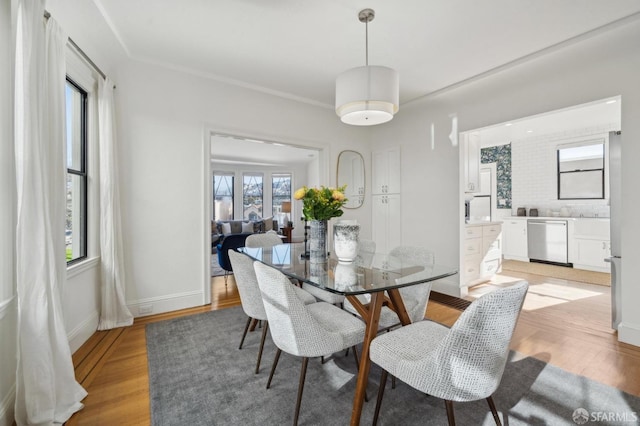 dining space featuring light wood-style flooring and baseboards