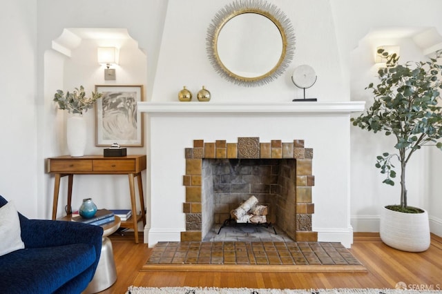 interior space featuring baseboards, a tiled fireplace, and wood finished floors