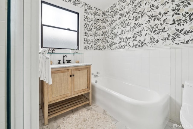 full bath featuring a bath, wallpapered walls, and a wainscoted wall