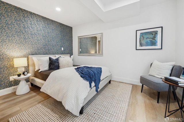 bedroom featuring recessed lighting, an accent wall, baseboards, light wood-style floors, and wallpapered walls