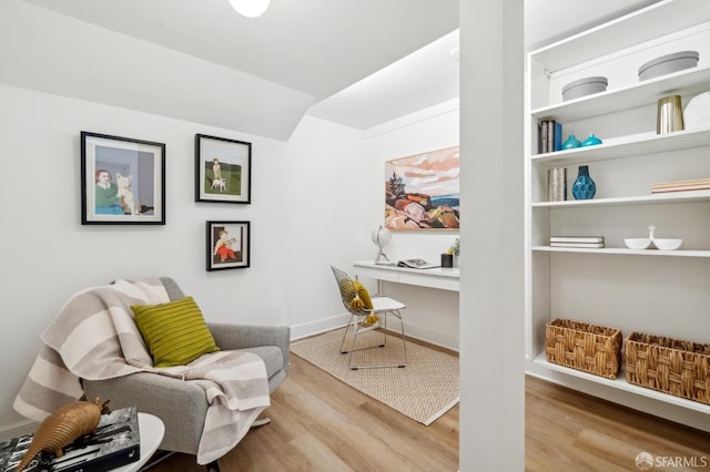 living area with lofted ceiling, wood finished floors, and baseboards