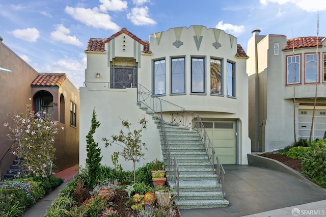 view of front facade featuring stucco siding, concrete driveway, stairway, an attached garage, and a tiled roof