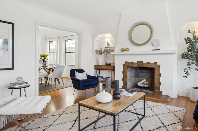 living room featuring a tiled fireplace, wood finished floors, and baseboards