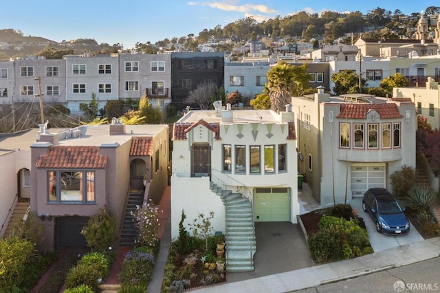 view of front of property featuring driveway, a residential view, stairway, and stucco siding